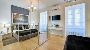 A modern bedroom with a bed, bedside tables, a desk, a TV, and a large mirror. - Prati Design Home (Roma)