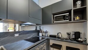 A modern kitchen with a black countertop, stainless steel appliances, and a built-in oven. - Prati Design Home (Roma)