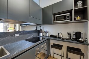 A modern kitchen with a black countertop, stainless steel appliances, and a built-in oven. - Prati Design Home (Roma)
