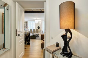 A hallway with a modern lamp, a glass coffee table, and a dining area in the background. - Prati Design Home (Roma)