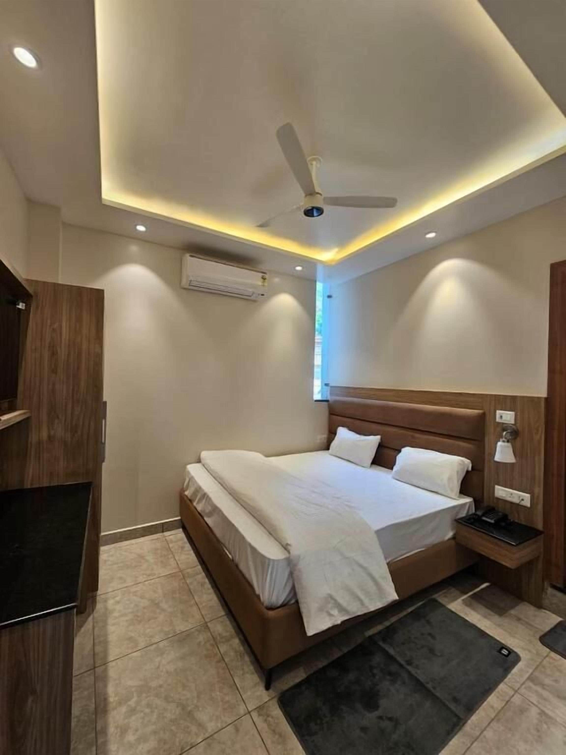 Un dormitorio moderno con cama, ventilador de techo, iluminación empotrada y mesita de noche.