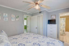 Un dormitorio con cama, ventilador de techo, cómoda y televisor.