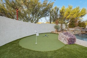 A miniature golf course with a green putting area, a white flag, and a rock feature. - 4BR Scottsdale Getaway with Pool, Spa & Game Room (Scottsdale)