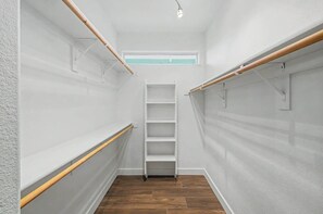 Ein schmaler begehbarer Kleiderschrank mit Holzbalken, einer eingebauten Ablagefläche und einem Oberlicht.