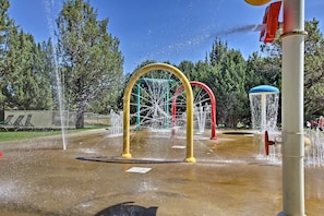 A water play area with multiple water jets and a playground structure.