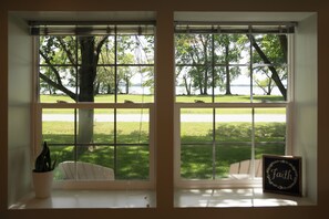 A room with a large window overlooking a grassy area and a body of water.