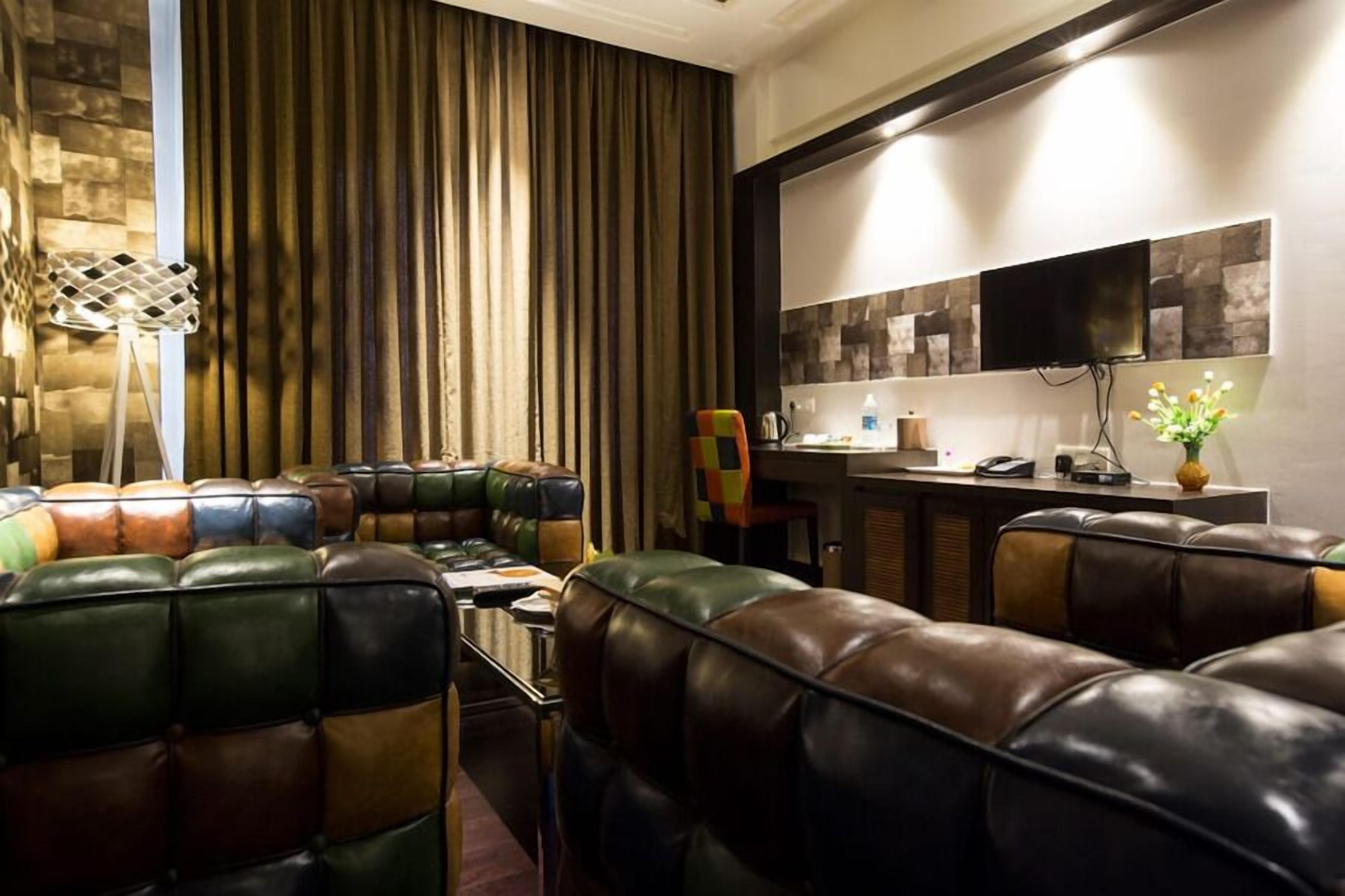 A modern lounge area with leather sofas, a bar, and a flat-screen TV.