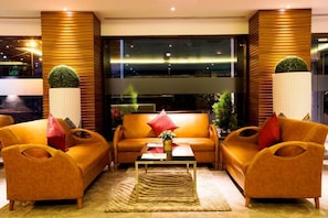 A modern living room with a sofa set, a coffee table, and decorative plants.