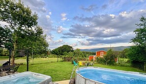 A backyard with a swimming pool, a hot tub, and a dining area with outdoor furniture.