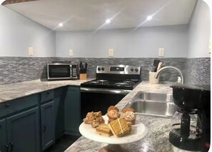 Eine Küche mit Mikrowelle, Herd und Spüle. Es gibt Schränke und eine Arbeitsplatte.