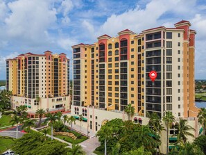 Un hôtel à plusieurs étages, reconnaissable à son emblème rouge, entouré de verdure et de palmiers.