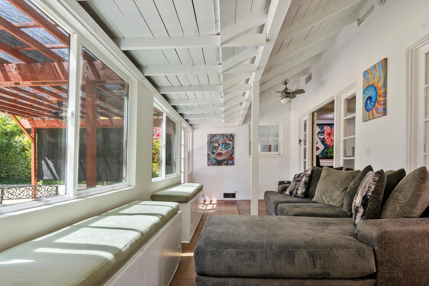 A spacious living area with a high ceiling, large windows, and a view of the outdoors.