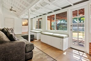 Ein geräumiges Wohnzimmer mit integriertem Sitzplatz, einer Couch und einem Deckenventilator.