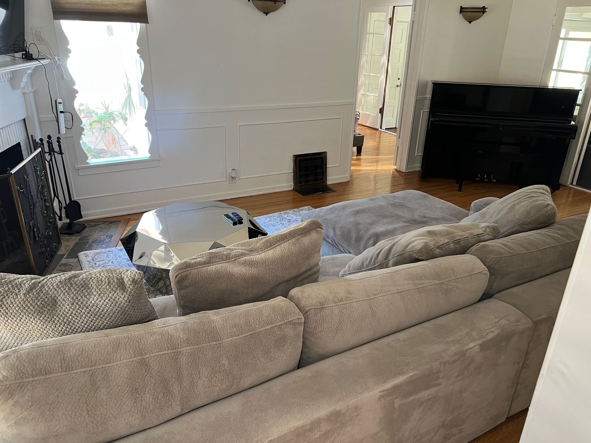 A living room with a beige sectional sofa, a small round table, and a flat-screen TV.