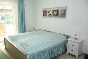 A bedroom with a bed, a nightstand, a dresser, and a window with curtains. - Large ground-floor vacation rental (house) with a terrace and carport in Hohenfelde (Hohenfelde)