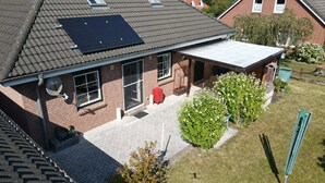 Een woongebouw met schuin dak, zonnepanelen, een bakstenen gevel en een klein voortuintje.