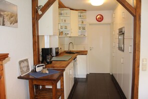 A kitchen with a wooden table, a microwave, a coffee maker, and a sink. - Large ground-floor vacation rental (house) with a terrace and carport in Hohenfelde (Hohenfelde)