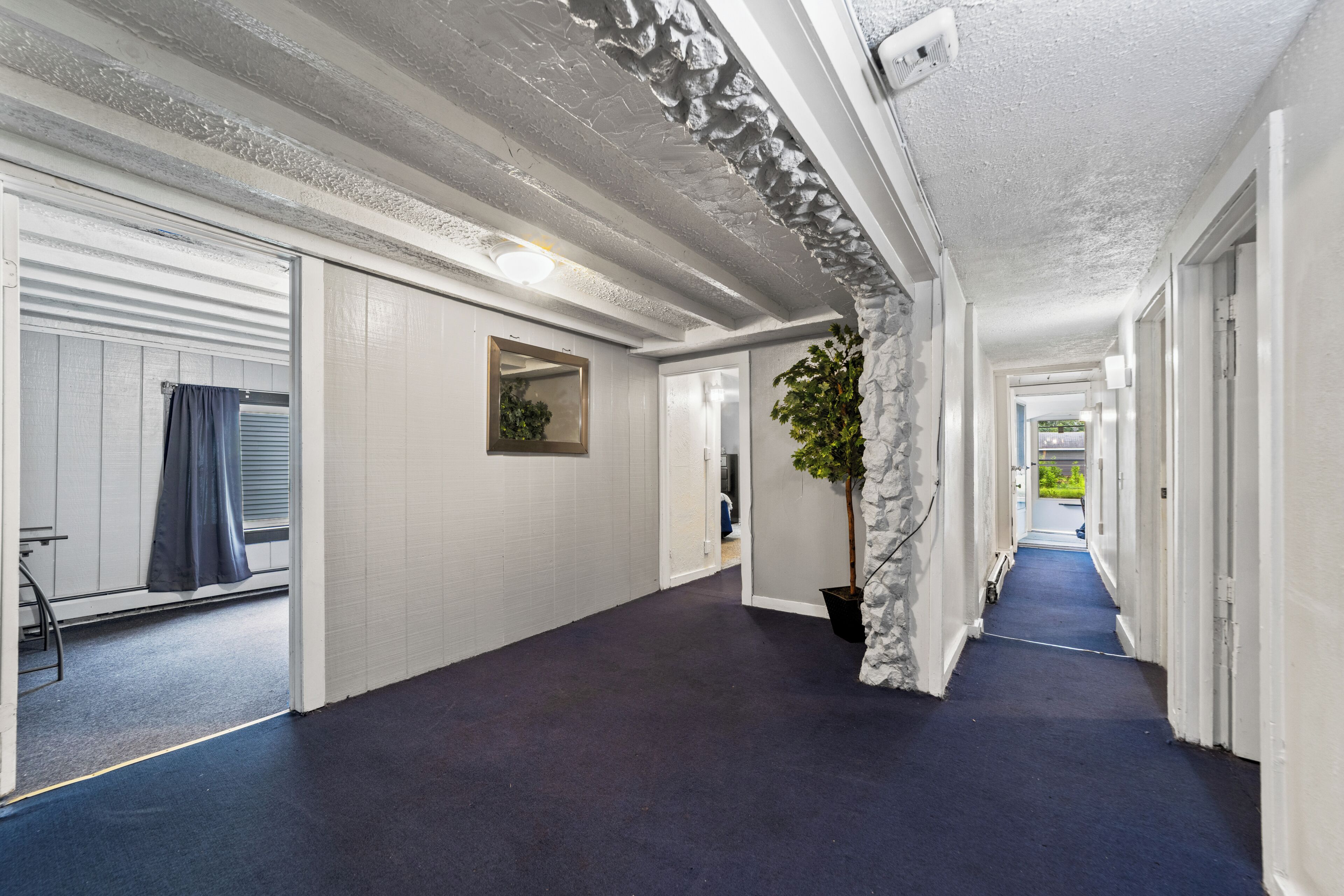 A hallway with a blue carpet, white walls, and a stone accent wall.