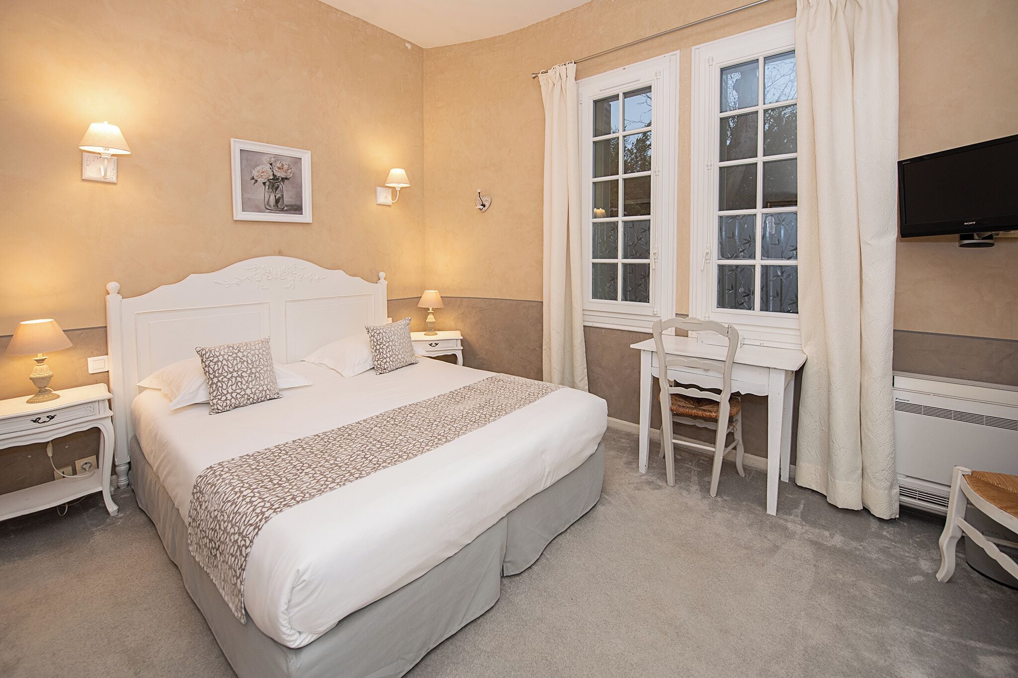 Une chambre à coucher avec un grand lit, des tables de chevet avec des lampes, un bureau et une chaise.