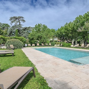 A swimming pool with lounge chairs and a grassy area.