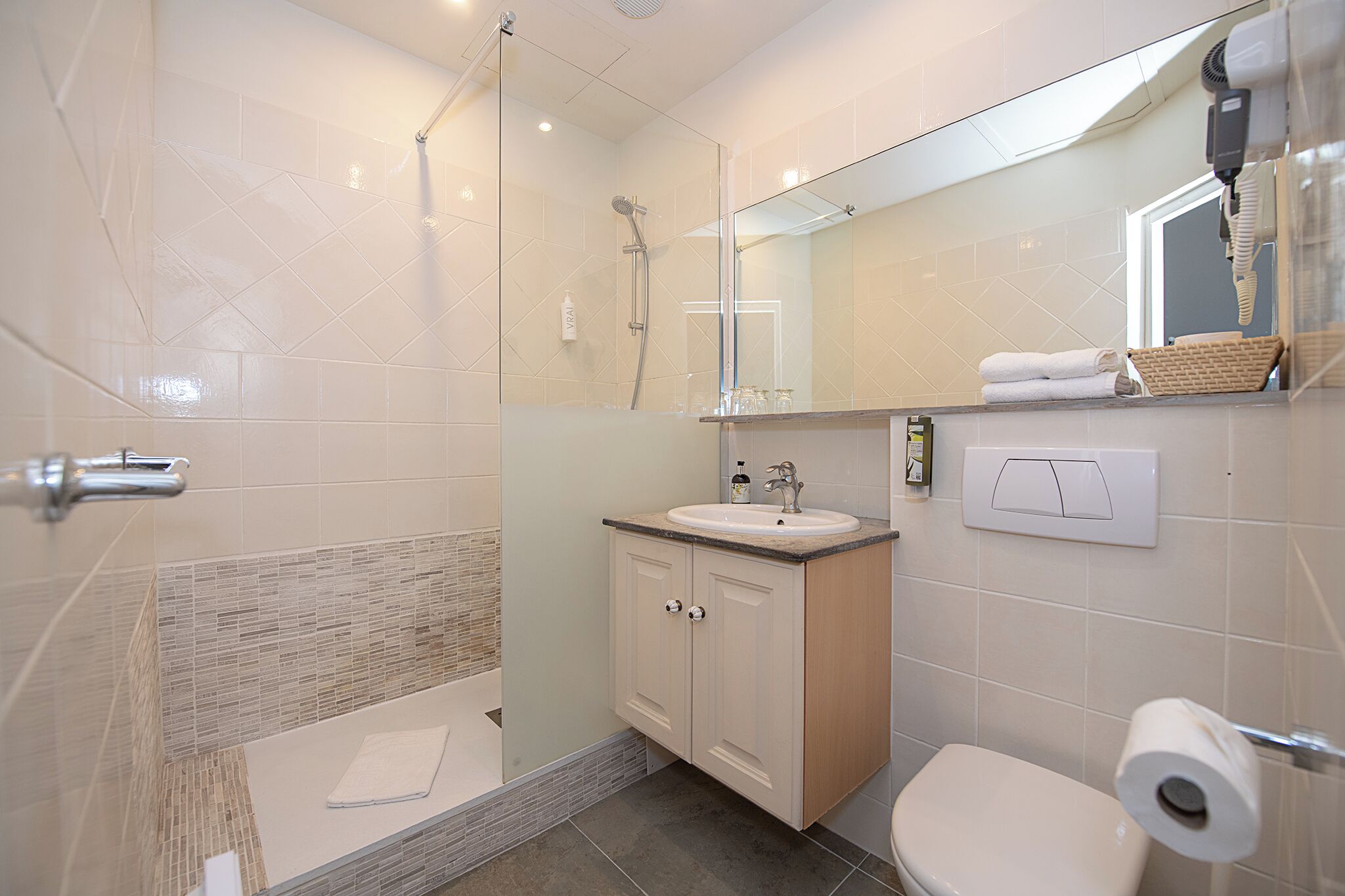 Un baño moderno con ducha de vidrio, lavamanos e inodoro.