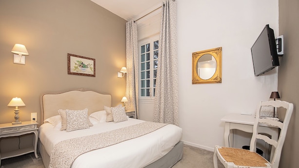A bedroom with a bed, bedside tables, a chair, a TV, and a window with curtains. - L'HERMITAGE (Pernes-les-Fontaines)