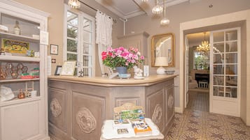 Ein gut beleuchteter Raum mit einer Theke, einem Blumentopf, einem Spiegel und einem Tisch mit Büchern.