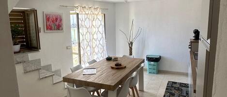 A dining area with a wooden table and chairs, a patterned rug, and a staircase leading to an upper level.