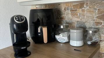 A kitchen counter with a coffee maker, a coffee machine, a water dispenser, and a jar with a spoon.