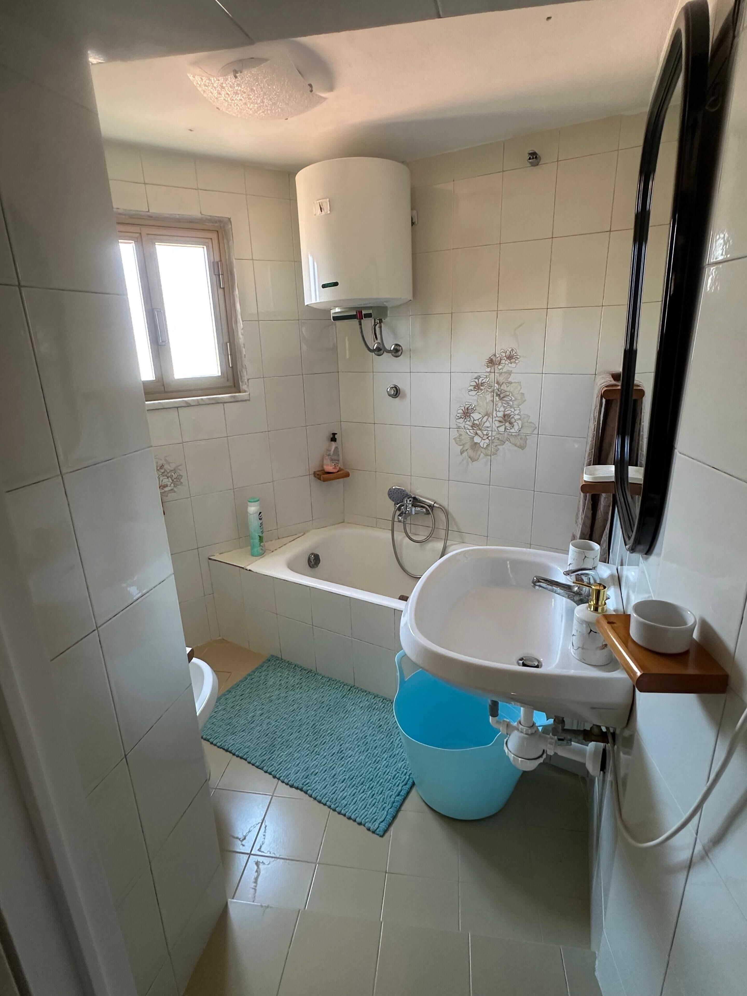 A bathroom with a bathtub, a sink, a toilet, and a window.