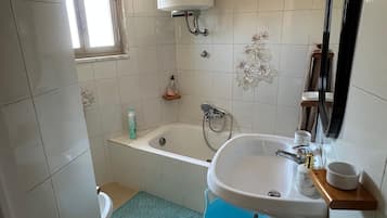 A bathroom with a bathtub, a sink, a toilet, and a window.