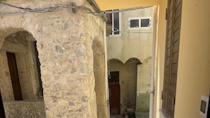 Una escalera conduce a un patio con paredes de piedra y una puerta de madera.