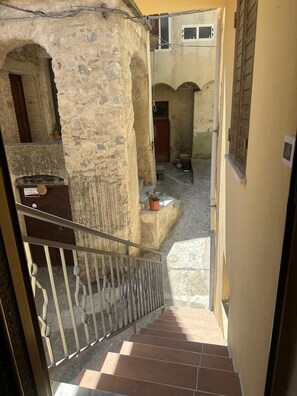A staircase leading to a courtyard with stone walls and a wooden door.