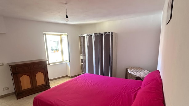 Un dormitorio con cama, cómoda, ventana y puerta.