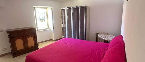 A bedroom with a bed, a dresser, a window, and a door.