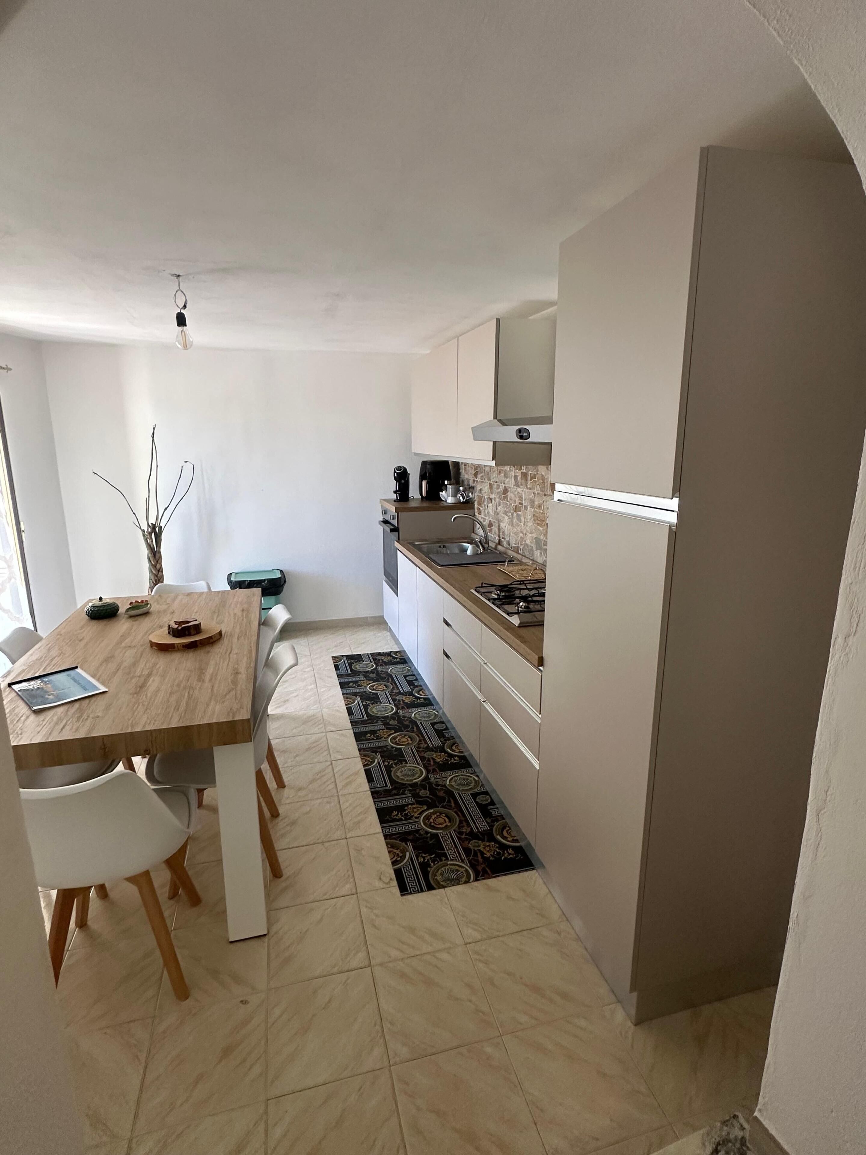 Una cocina compacta con una mesa de comedor, sillas, cafetera y estufa.