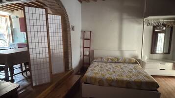A bedroom with a wooden floor, a bed with a patterned bedspread, a red ladder, and a traditional Japanese shoji screen.