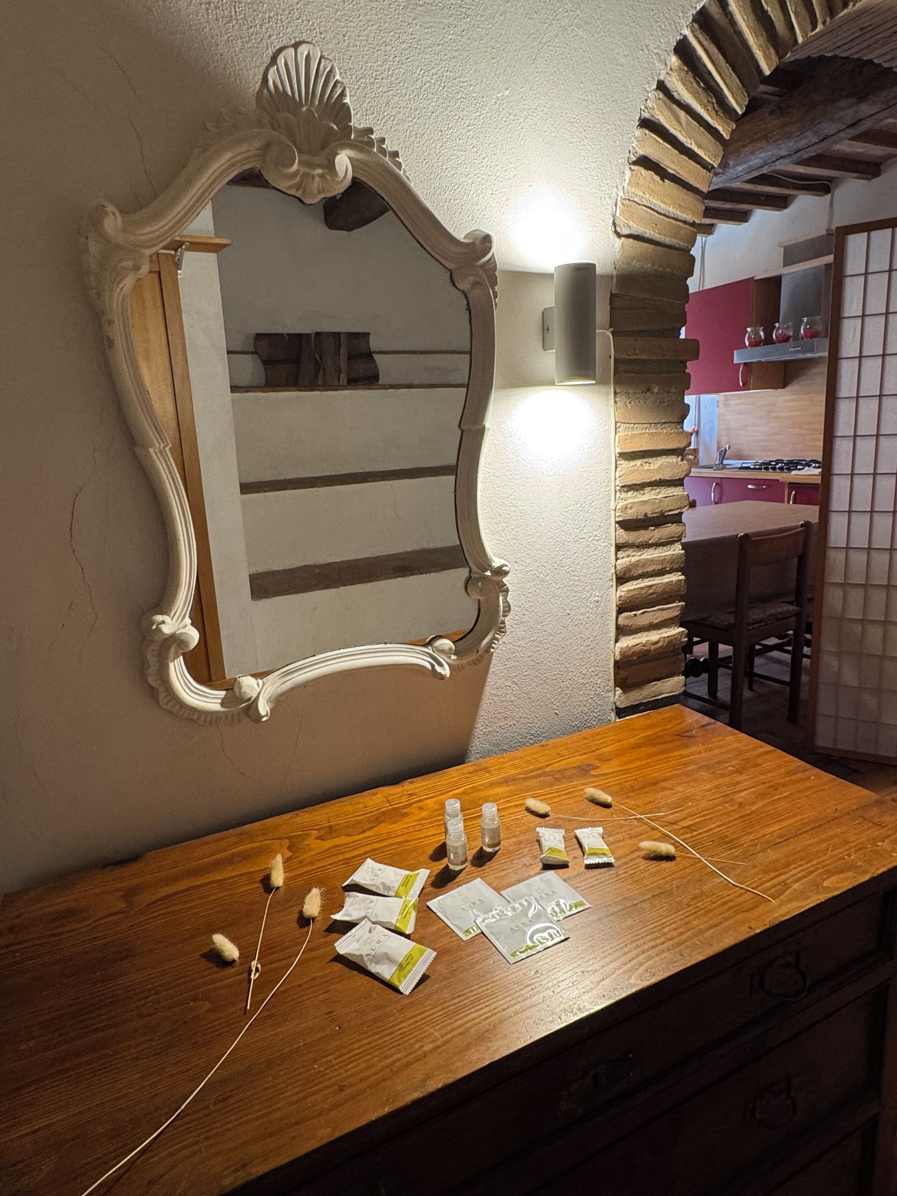 A wooden vanity with a decorative mirror and a wall-mounted light.