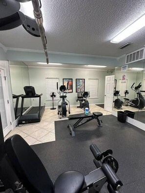 Une salle de sport équipée de matériel d’exercice, d’un tapis de course et d’un miroir.