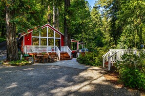 A cabin with a deck, surrounded by trees.