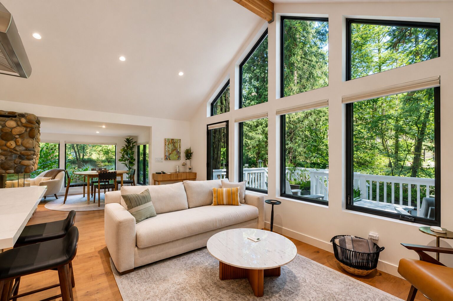 A spacious living area with a large window, a stone wall, and a dining area.