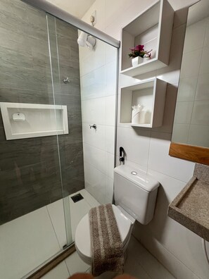 A modern bathroom with a glass-enclosed shower, a toilet, and a sink. - 401 Suite Elegante e Moderna (Belém)