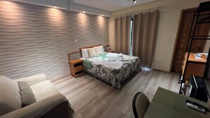 A hotel room with a bed, bedside table, chair, and a desk with a remote control. - 401 Suite Elegante e Moderna (Belém)