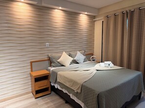 A neatly made bed with a quilted cover, a bedside table with a drawer, and a wall with a textured pattern. - 401 Suite Elegante e Moderna (Belém)