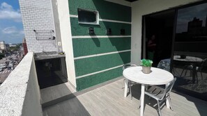A balcony with a table and chairs, a potted plant, and a view of the street. - 401 Suite Elegante e Moderna (Belém)