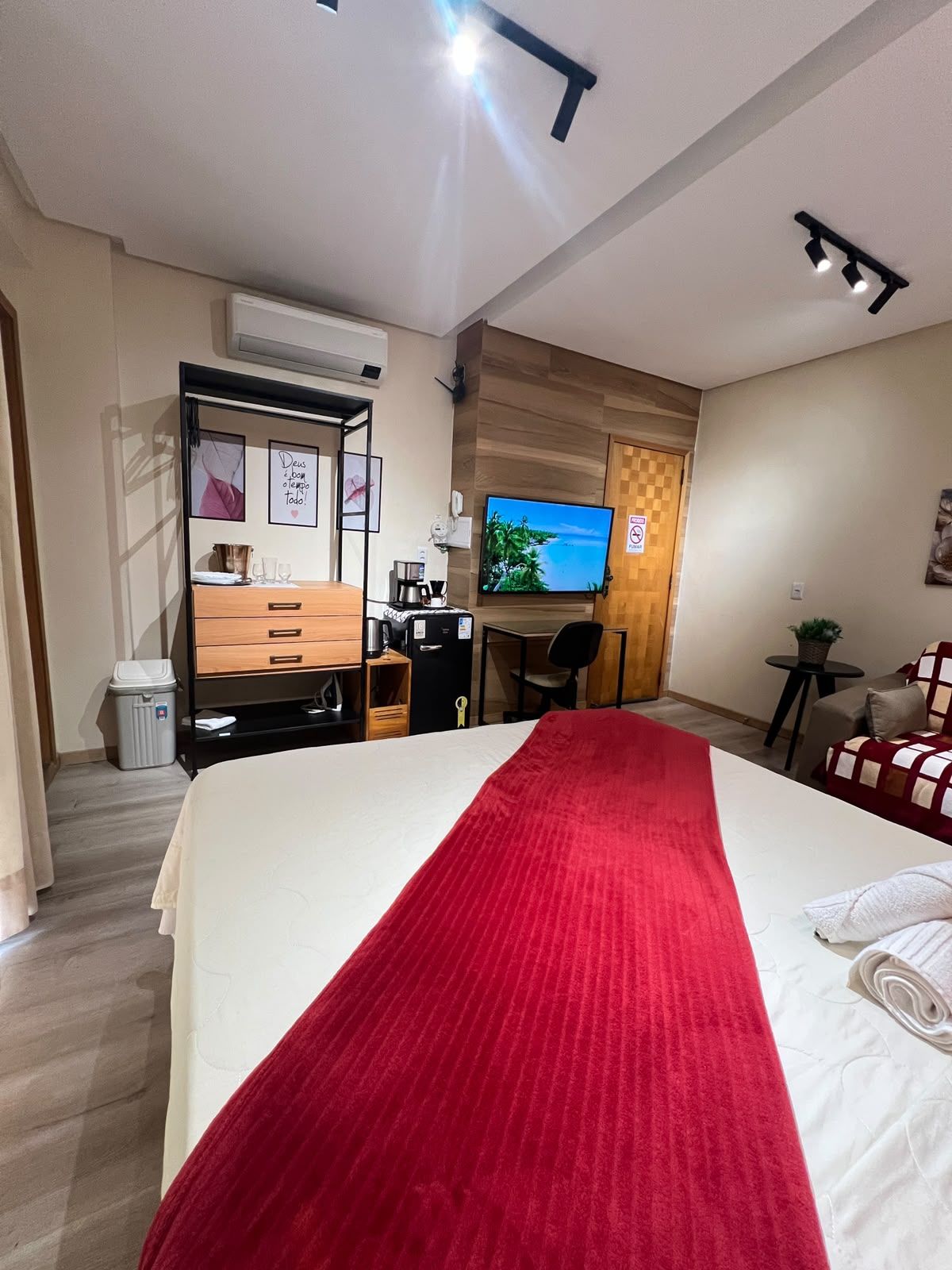 A hotel room with a bed, a desk, a television, and a small seating area.