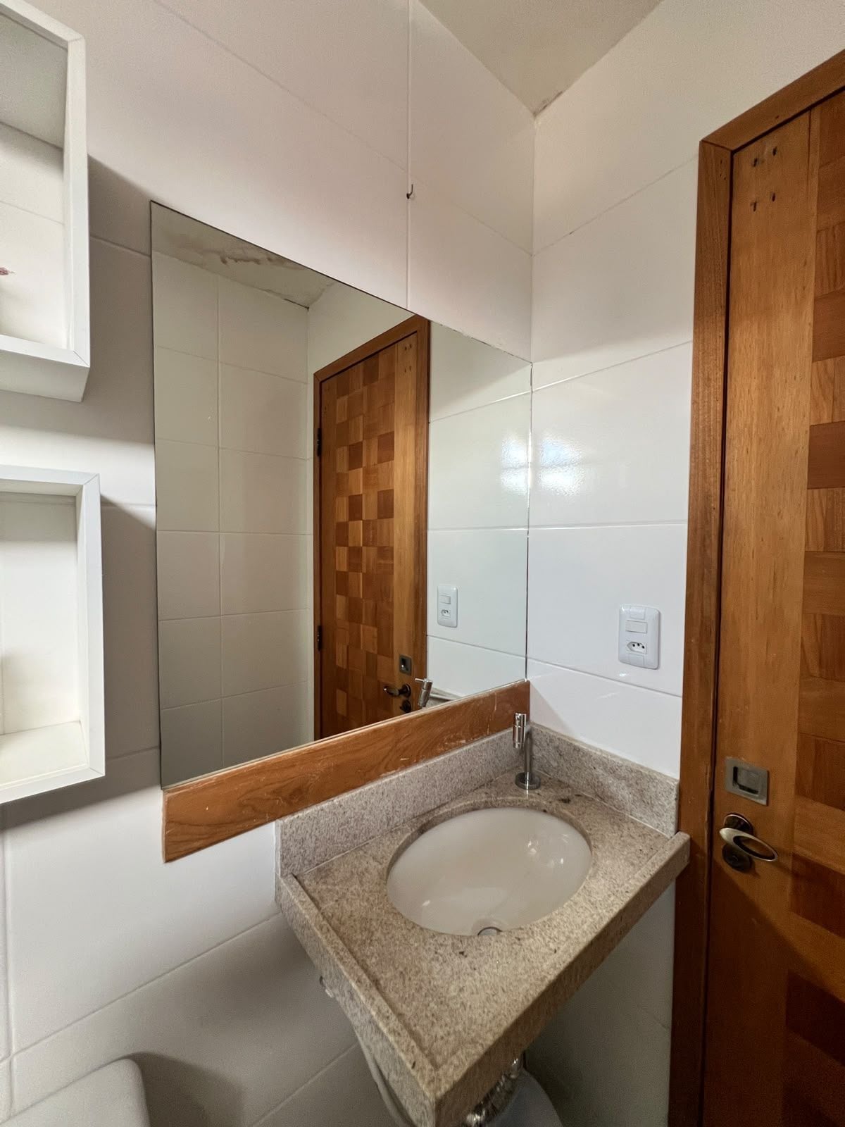 A bathroom with a granite sink, a wooden door, and a mirror with a wooden frame.