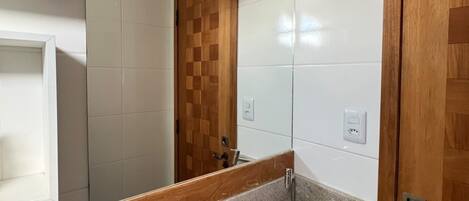 A bathroom with a granite sink, a wooden door, and a mirror with a wooden frame.
