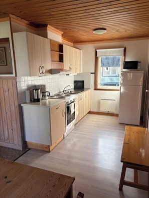 A kitchen with wooden cabinets, a stove, a microwave, and a refrigerator.
