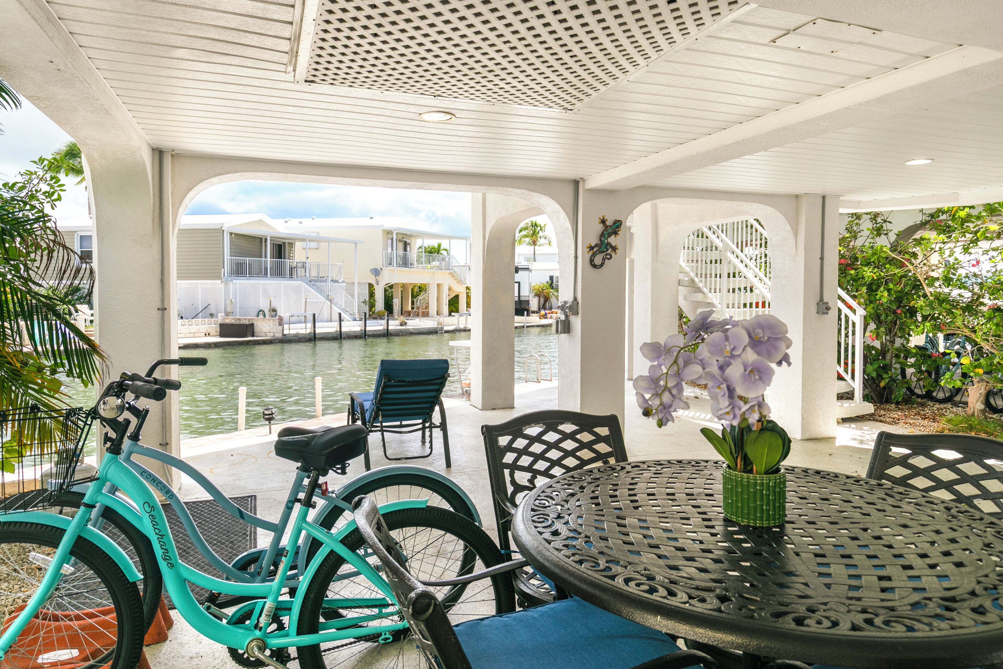 Un espace extérieur abrité comprenant une piscine, des vélos et une table décorée de fleurs.